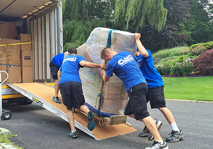 Clancy movers pushing cart of package to courier